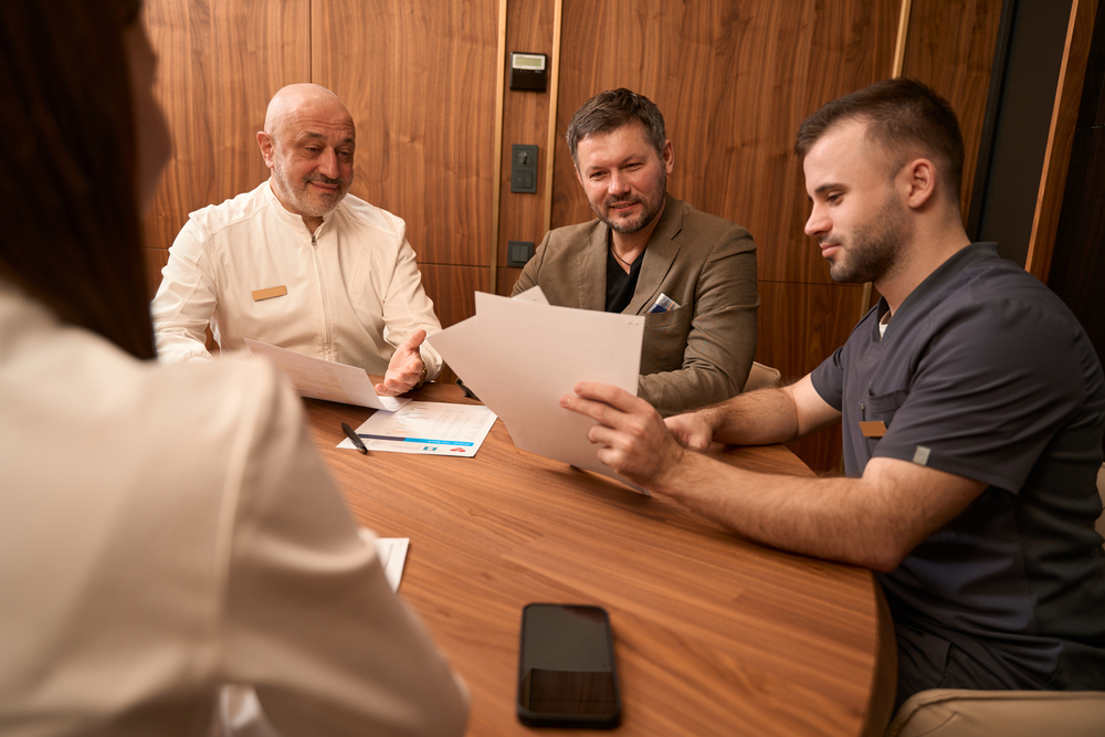 physicians discussing papers with man at desk